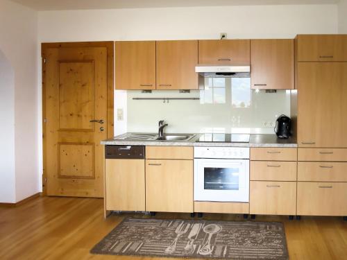 a kitchen with wooden cabinets and a sink and a door at Apartment Moarerlechenhof - FGZ337 by Interhome in Hart im Zillertal