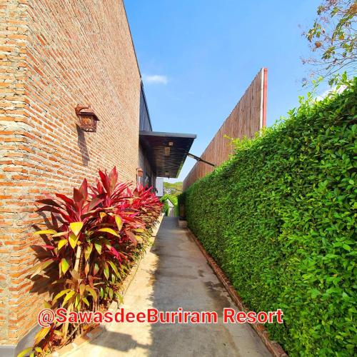 a brick building with plants next to a sidewalk at Sawasdee​ Buriram​ Resort in Buriram