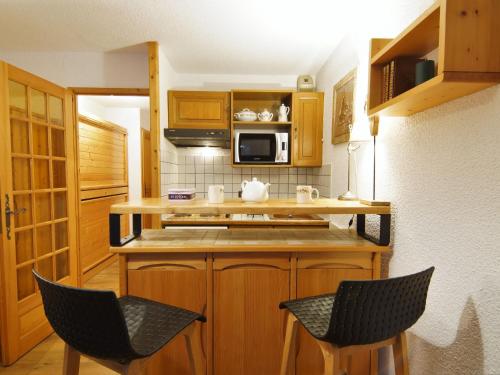 a small kitchen with two chairs and a microwave at Studio Clos du Savoy-22 by Interhome in Chamonix