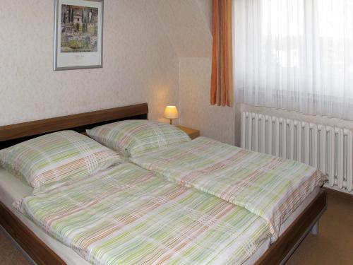 a bed with a striped comforter in a bedroom at Apartment Am Park by Interhome in Raben Steinfeld