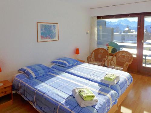 a bedroom with a bed with blue plaid sheets and a window at Apartment Victoria B 7 by Interhome in Crans-Montana