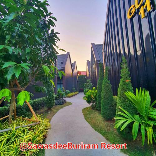 a walkway through a garden next to a building at Sawasdee​ Buriram​ Resort in Buriram