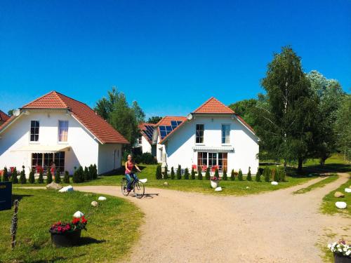 a woman riding a bike in front of two white houses at Holiday Home Ferienpark Verchen-2 by Interhome in Verchen