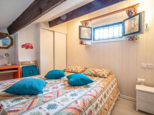 a bedroom with a bed with blue pillows and a window at Holiday Home Les Maisons de la Plage-4 by Interhome in Le Grau-du-Roi