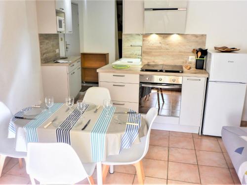 濱海聖皮埃爾的住宿－Apartment Les Terrasses de la Méditérranée-1 by Interhome，厨房配有带白色椅子的桌子和炉灶。