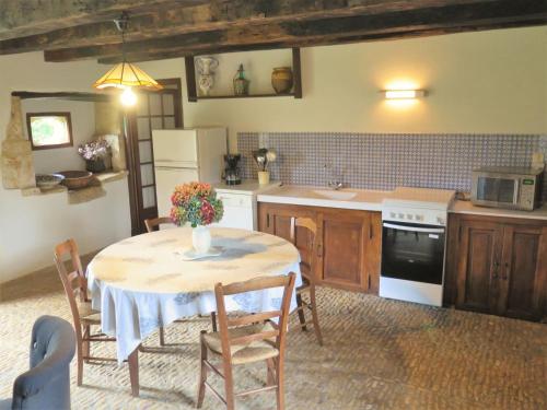 une cuisine avec une table avec des chaises et un réfrigérateur dans l'établissement Holiday Home Le Petit Gîte by Interhome, à Jayac