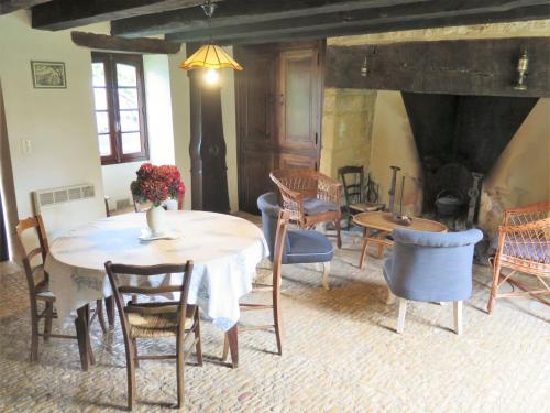Un comedor con mesa y sillas y chimenea. en Holiday Home Le Petit Gîte by Interhome, en Jayac