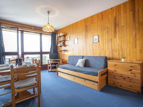 a living room with a blue couch and wooden walls at Apartment Cote Louve by Interhome in La Toussuire