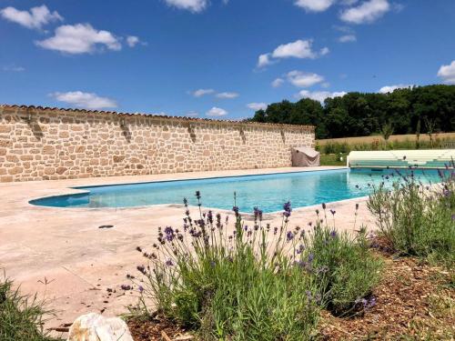 - une piscine à côté d'un mur en pierre dans l'établissement 5 bedroom house with private pool, S Dordogne, à Monpazier