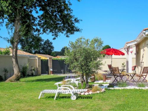 a yard with a white bench and a red umbrella at Holiday Home Mogador - CCP115 by Interhome in Carcans