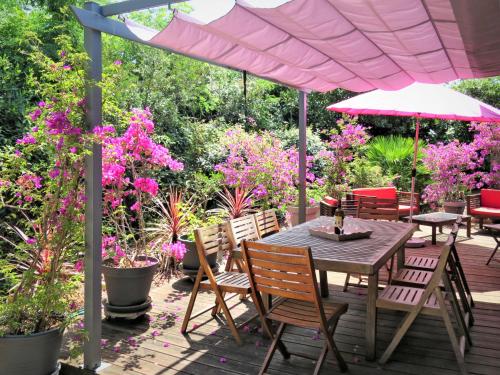 un patio con mesa, sillas y flores rosas en Holiday Home Les Bains Douche - SUL180 by Interhome, en Soulac-sur-Mer