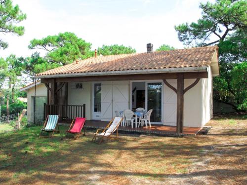 a small white house with chairs and a table at Holiday Home Anne Marie by Interhome in Lacanau-Océan