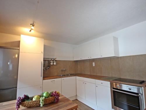 a kitchen with white cabinets and a bowl of fruit on a table at Holiday Home Ötztal by Interhome in Oetz