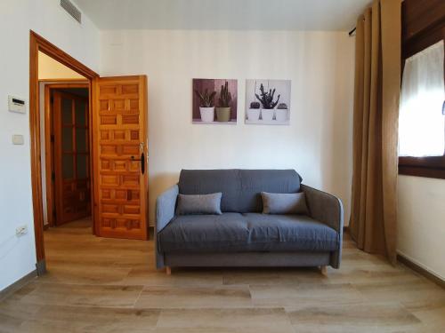 a living room with a blue couch and a door at Casa La Plazuelilla in Chinchón
