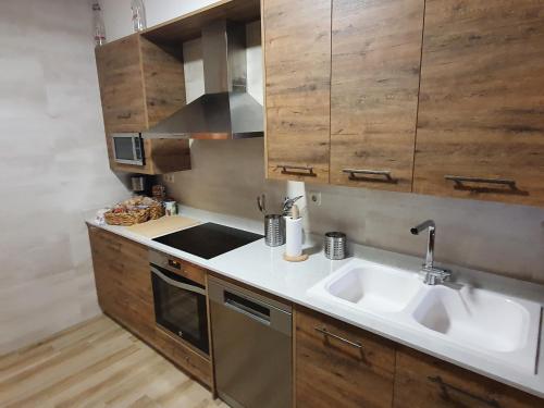 a kitchen with two sinks and wooden cabinets at Casa La Plazuelilla in Chinchón