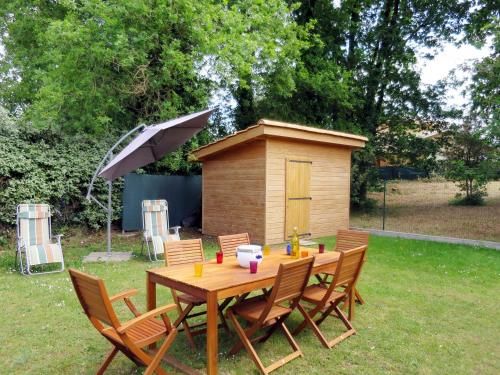 uma mesa de madeira e cadeiras num quintal com uma casa de cão em Holiday Home Mimosa - SUL135 by Interhome em Soulac-sur-Mer