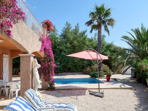 une terrasse avec des chaises et un parasol ainsi qu'une piscine dans l'établissement Holiday Home Yalou by Interhome, à Cavalaire-sur-Mer