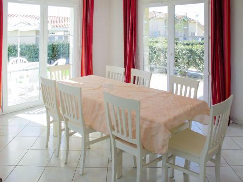 comedor con mesa, sillas y ventanas en Holiday Home Résidence Indigo II - BPL326 by Interhome en Biscarrosse-Plage