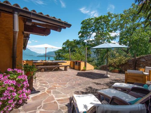 eine Terrasse mit Tischen und Sonnenschirmen mit Blick auf das Wasser in der Unterkunft Holiday Home Villa Madda by Interhome in Dongo