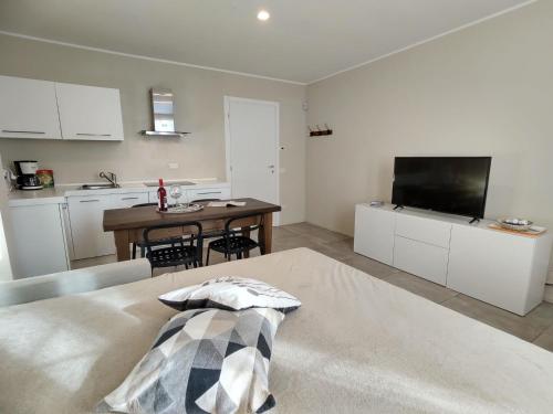 a living room with a table and a kitchen with a television at Apartment Federico by Interhome in Olgiasca