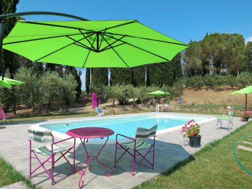 una sombrilla verde sobre una mesa y sillas junto a una piscina en Apartment Conte Francesco I-2 by Interhome, en Certaldo