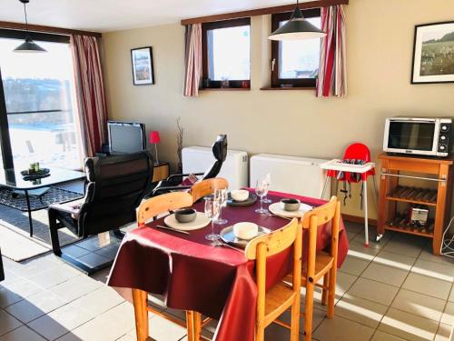 ein Wohnzimmer mit einem Tisch, Stühlen und einem TV in der Unterkunft Holiday Home Au bord du Lac-1 by Interhome in Bütgenbach