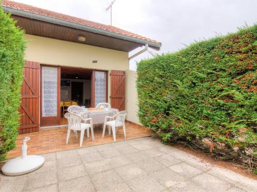 a patio with a table and chairs and a hedge at Holiday Home Sicard-6 by Interhome in Mimizan-Plage