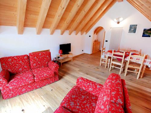 een woonkamer met twee rode banken en een tafel bij Apartment Albergo Diffuso - Cjasa de Barce-2 by Interhome in Barcis