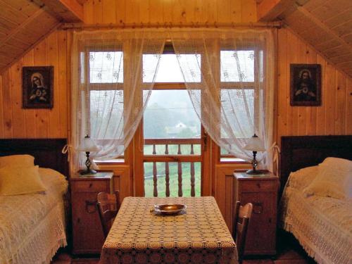 a bedroom with two beds and a table and a window at Holiday Home Borówna by Interhome in Lipnica Górna