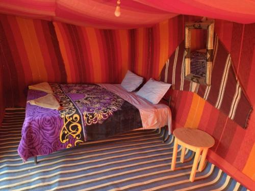 una camera con un letto in una stanza a righe di Chegaga Nomad Camp a El Gouera
