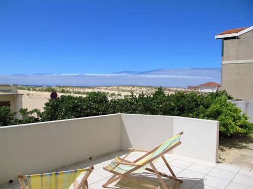 two chairs sitting on a balcony with a view of the beach at Apartment Capama-1 by Interhome in Mimizan-Plage