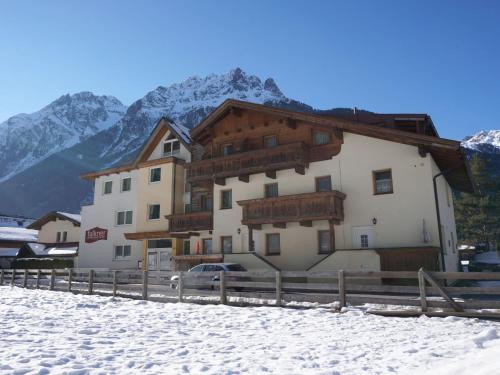 a building in the snow with mountains in the background at Apartment Falkner-7 by Interhome in Oberlängenfeld
