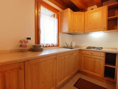 una cucina con armadi in legno, lavandino e finestra di Holiday Home Albergo Diffuso - Cjasa Paron Cilli by Interhome a Barcis
