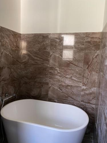 a bath tub in a bathroom with a stone wall at Ta 溫泉會館 in Jiaoxi