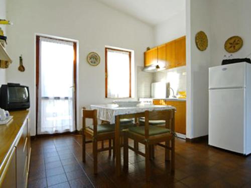 eine Küche mit einem Tisch und Stühlen sowie einem weißen Kühlschrank in der Unterkunft Apartment Reale Marina - REI207 by Interhome in Costa Rei
