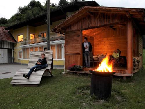 a man sitting on a bench next to a fire at Apartment Schwarzwald 6 EG by Interhome in Radenthein