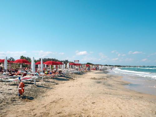 una playa con gente sentada en sillas y sombrillas en Holiday Home Happy Camp Mobilhome Torre Rinalda by Interhome, en Lecce