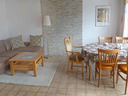 uma sala de estar com uma mesa e cadeiras e um sofá em Holiday Home Adda by Interhome em Neßmersiel