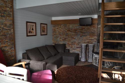 a living room with a couch and a brick wall at Saaritupa Apartment Saariselkä in Saariselka