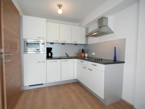 a white kitchen with white cabinets and a microwave at Apartment Alpenrose-2 by Interhome in See