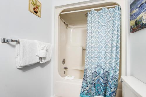 a bathroom with a shower with a blue shower curtain at The Inn at St. Thomas Square #1203A in Panama City Beach