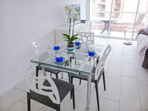 uma mesa de jantar de vidro com cadeiras e flores em Apartment Le Méditerranée-2 by Interhome em Fréjus