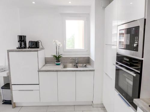 une cuisine blanche avec un évier et un micro-ondes dans l'établissement Apartment Le Méditerranée-2 by Interhome, à Fréjus
