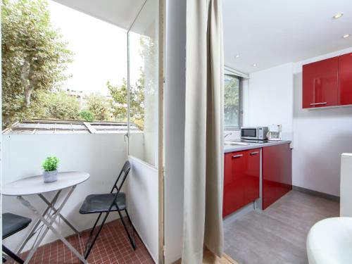 une cuisine avec des placards rouges, une table et une fenêtre dans l'établissement Apartment Le Corsaire-5 by Interhome, à Cannes