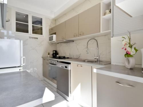 La cuisine blanche est équipée d'un évier et d'un réfrigérateur. dans l'établissement Apartment Le Rossini by Interhome, à Nice