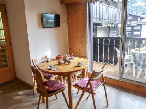 Cette chambre dispose d'un balcon avec une table et des chaises en bois. dans l'établissement Apartment Clos du Savoy-23 by Interhome, à Chamonix-Mont-Blanc