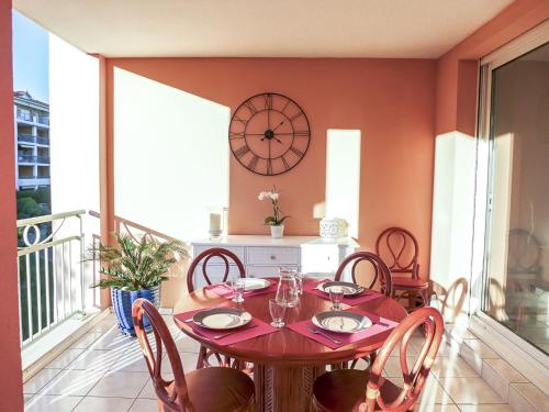 une salle à manger avec une table, des chaises et une horloge dans l'établissement Apartment Les Calanques du Parc-2 by Interhome, à Saint-Aygulf