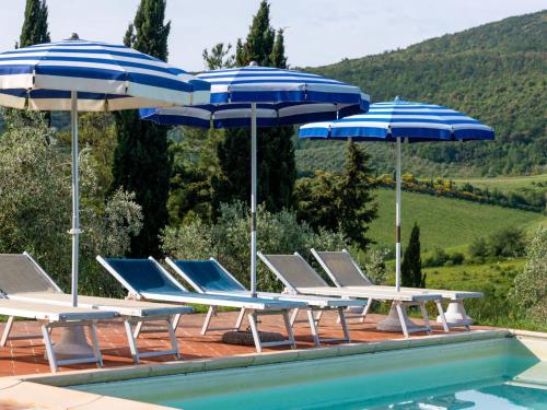 a group of chairs and umbrellas next to a pool at Apartment Le Sodole - Petunia by Interhome in San Gimignano