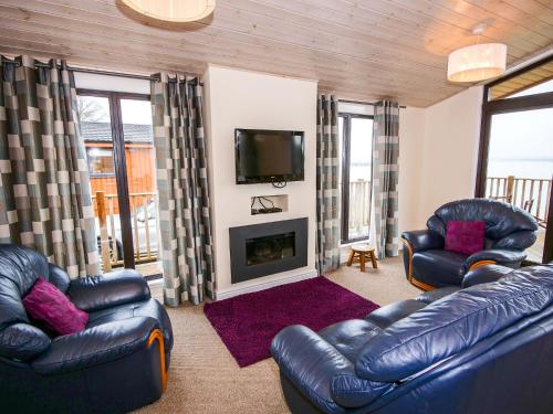 Chalet Loch Leven Lodge by Interhome في Ballingry: غرفة معيشة مع كنبتين جلديتين وتلفزيون