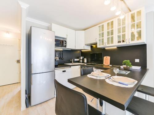 Il comprend une cuisine équipée d'un réfrigérateur et d'une table avec des chaises. dans l'établissement Apartment Le Beach Garden by Interhome, à Cannes